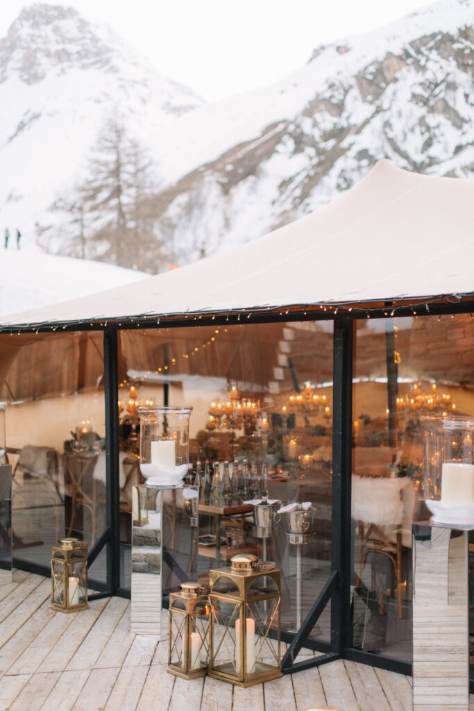 Clear-walled stretch tent warmly lit for a wedding in snowy mountains