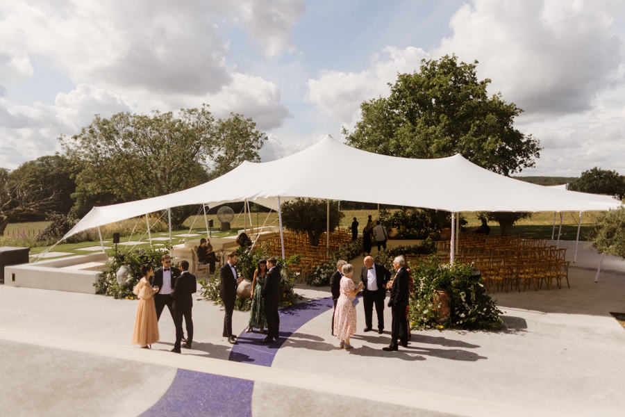 Guests arriving for a wedding ceremony under a sculpted stretch tent