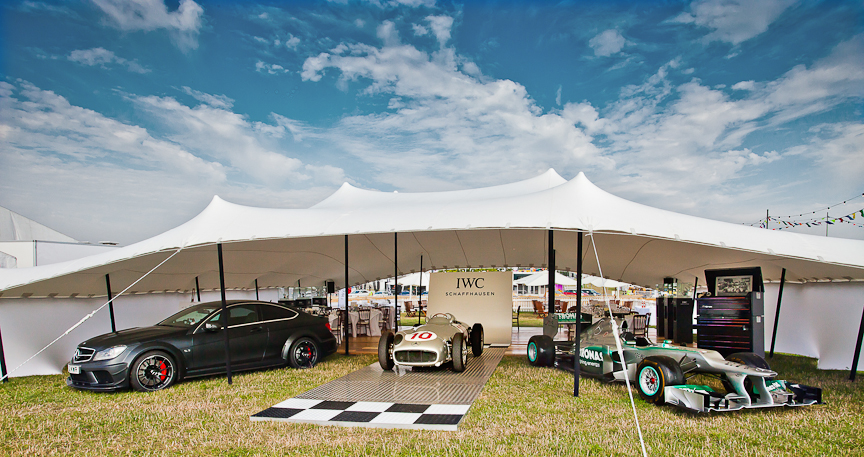 Race cars displayed under an open-fronted white stretch canopy
