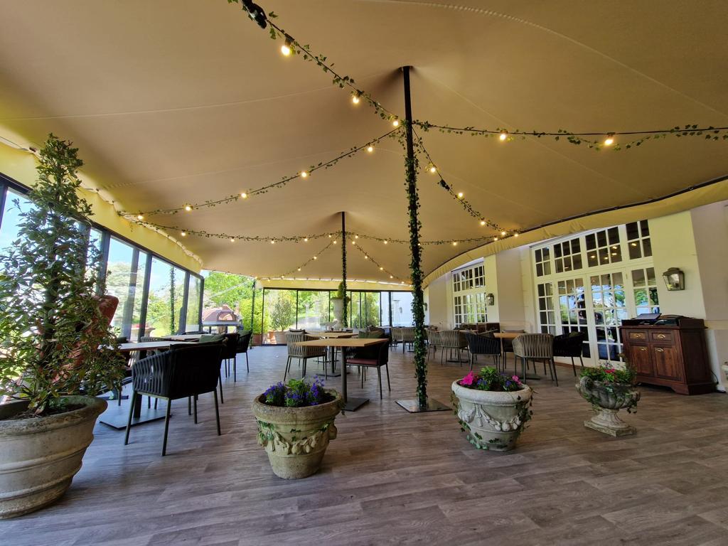 Beige stretch tent over a furnished terrace with warm string lights