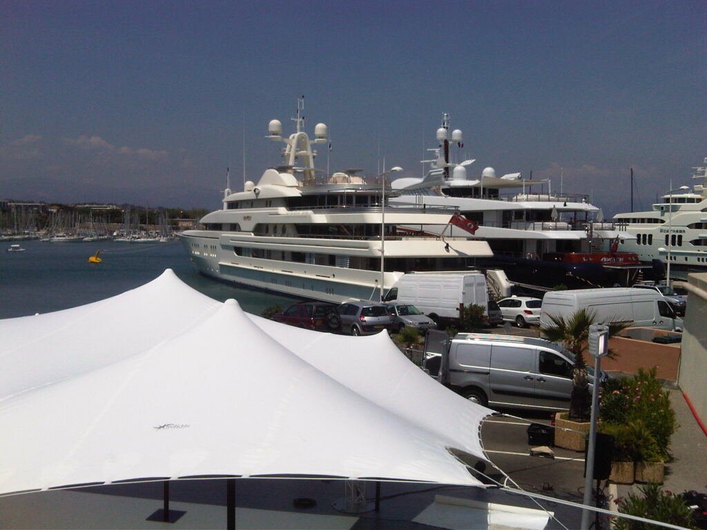 Freeform white stretch tent on a marina beside moored yachts
