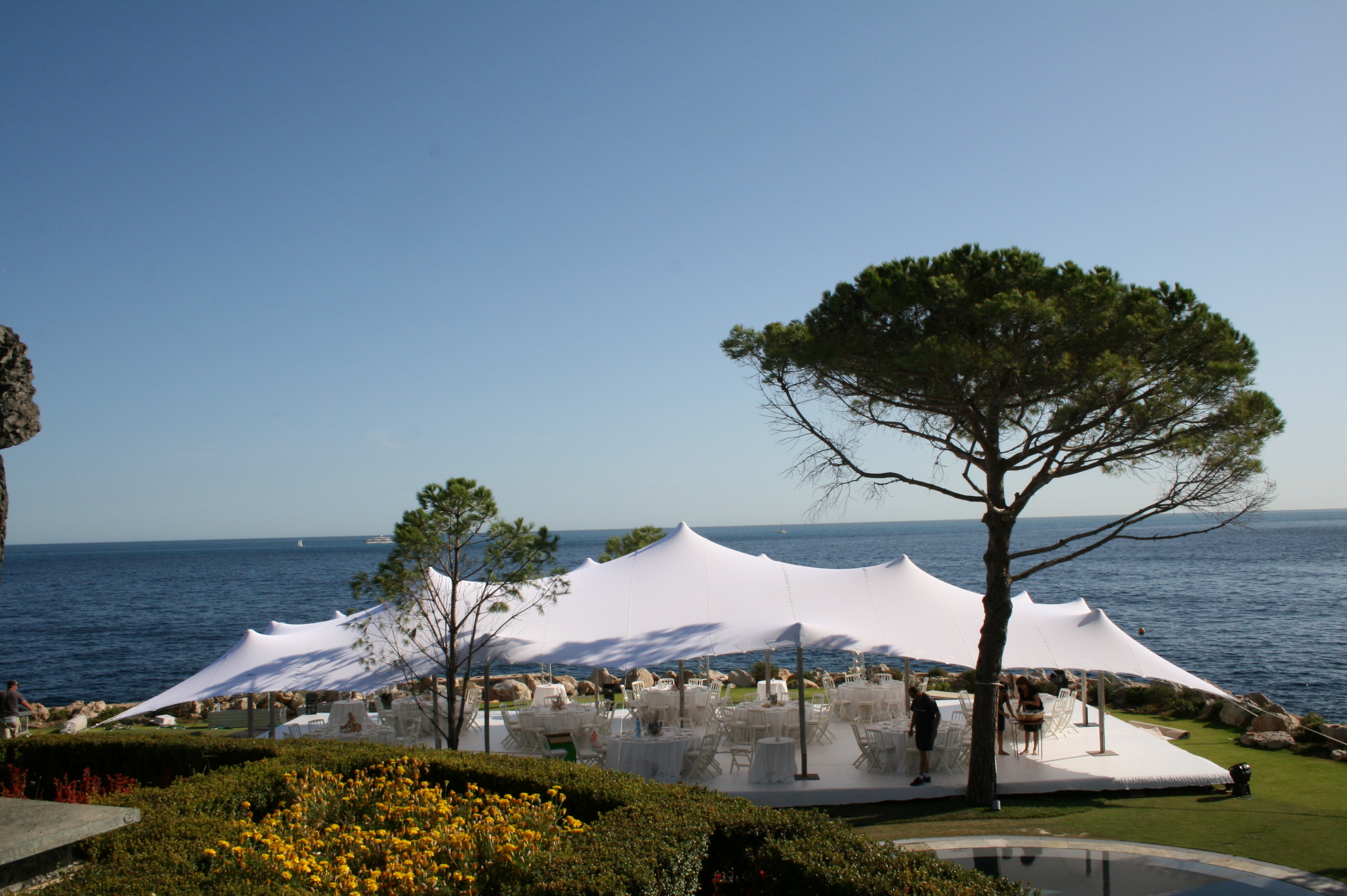 Wedding reception under a stretch tent on a coastal lawn above the sea