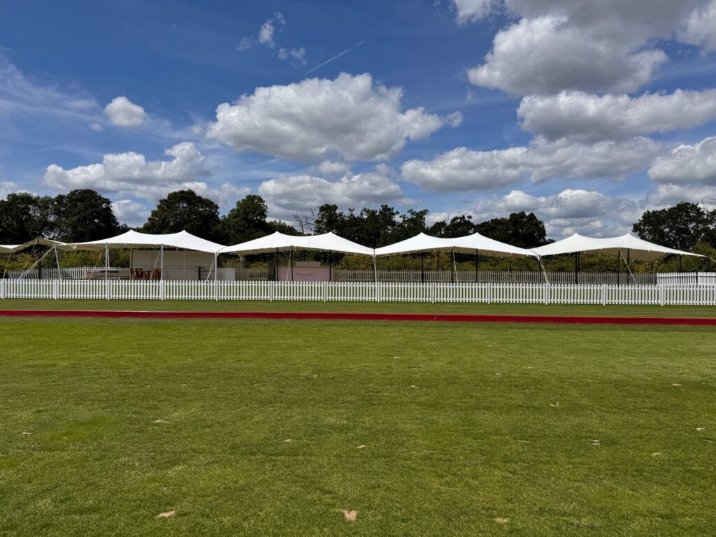 Long modular stretch tent with an enclosed service bay on a grass field