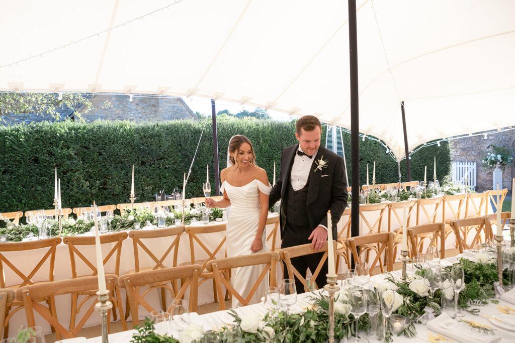 Bride and groom at a banquet table under an open-sided stretch tent