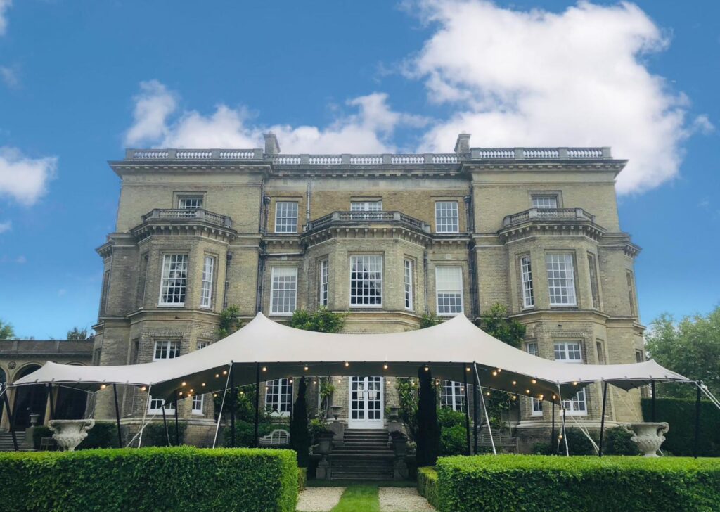 Open-sided white stretch tent with festoon lighting on a country estate lawn