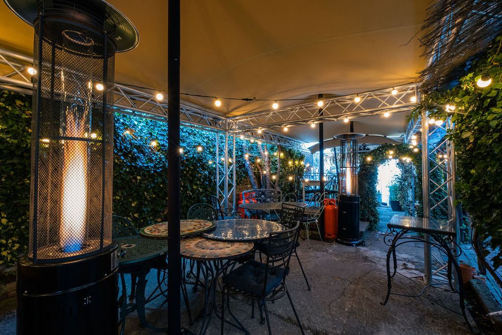 Garden terrace party set under a stretch tent with festoon lighting at dusk