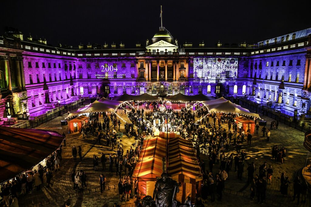 Linked stretch tents lit for a night gala in a historic courtyard