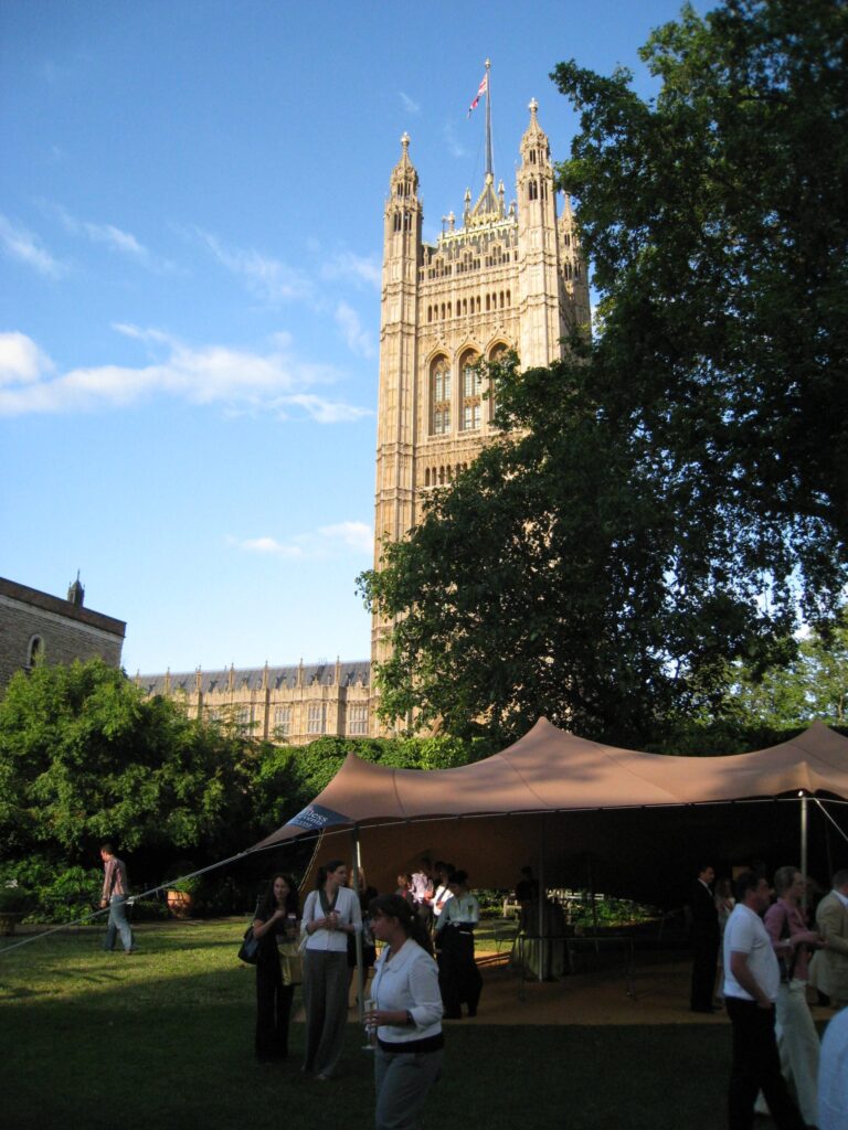 Standing reception under a tan stretch tent on a garden lawn