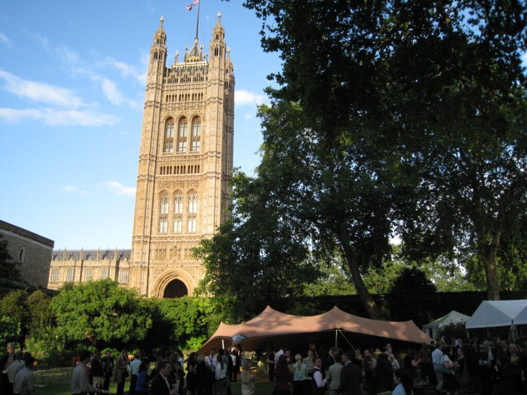 Guests at a corporate reception under a peaked tan stretch tent